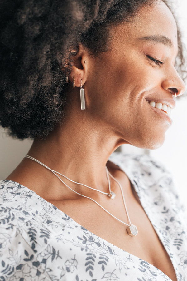 a farther photo of the sterling silver bar cremation dangle earrings being worn by a model along with other memorial jewelry with ashes by close by me