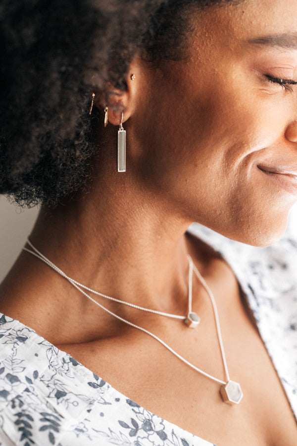 close by me's memorial earrings with ashes on a model from a medium distance away