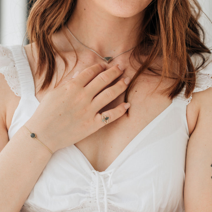 A model with red hair wears a cream colored dress and has the bolo chain cremation bracelet in 14k yellow gold on her wrist.