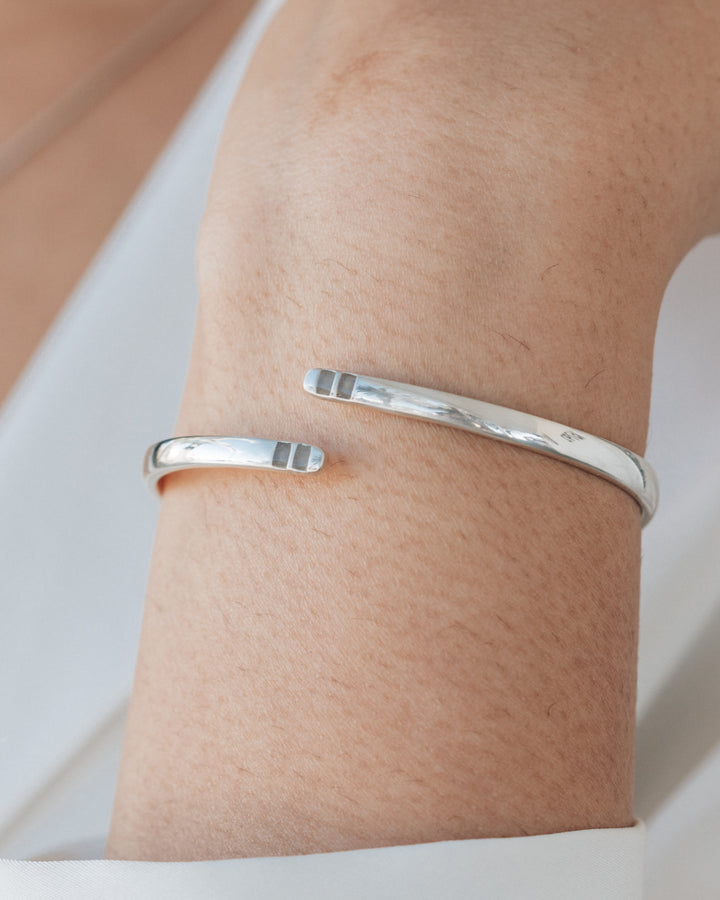 A close up showing a model wearing the rhodium plated sterling silver bypass hinged cuff bracelet with ashes