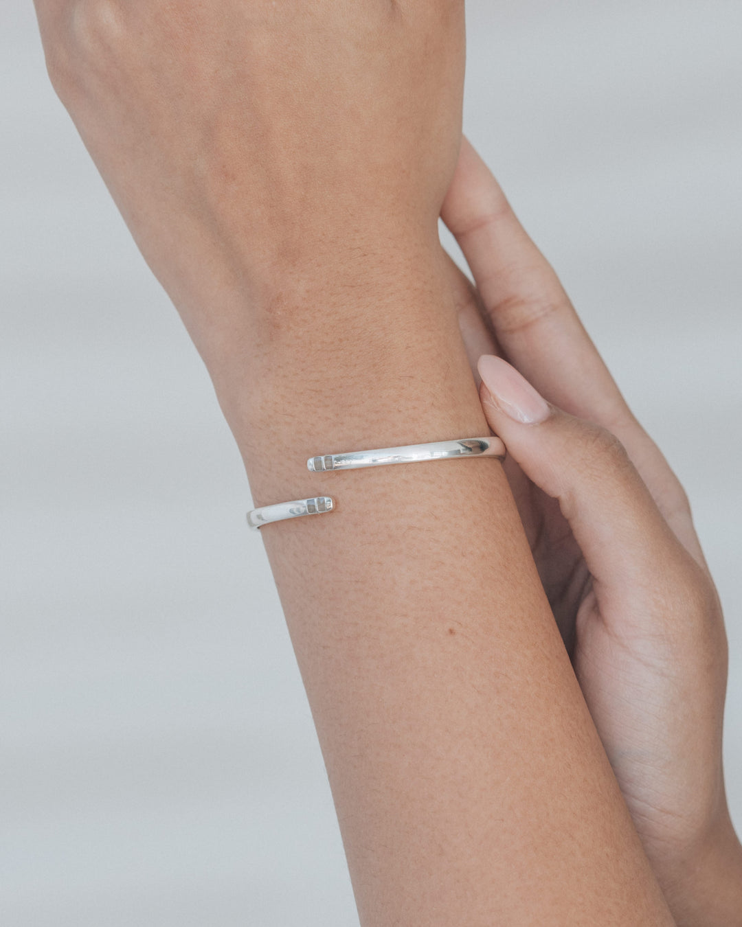 A photo showing the bypass hinged cuff bracelet with cremains on a model's wrist held up against a white background