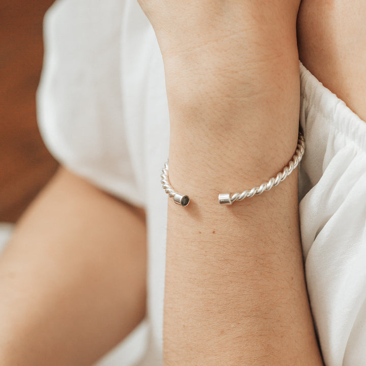 Sterling Silver cable cuff bracelet with cremated remains solidified on the wrist of a model wearing a white dress