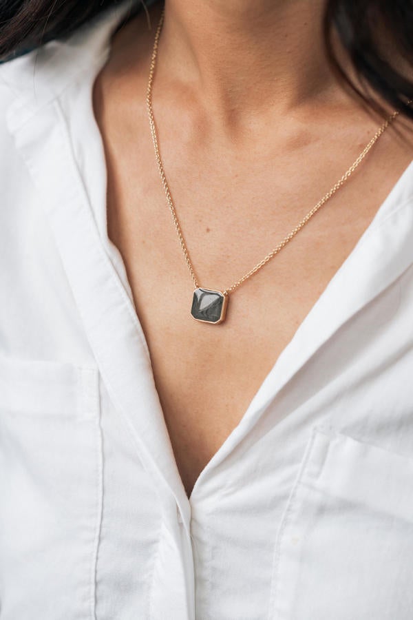 The 14k yellow gold cushion art deco cremation necklace designed and set with ashes by close by me jewelry being worn by a tan model in white button-down