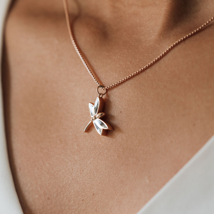 This photo shows a close up of a model wearing close by me jewelry's 14K Rose Gold Dragonfly Pendant with ashes