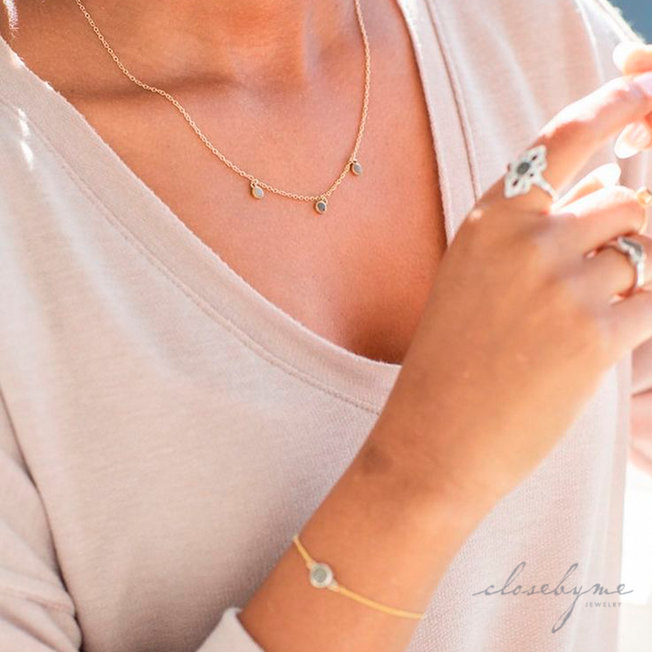 This close up photo shows the 14K Yellow Gold Drop Necklace with Cremated Remains set into Three Components by close by me jewelry being worn by a model