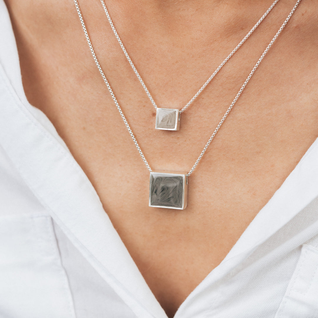 A close up showing both sizes of the Square Cremation Sliding Necklaces in Sterling Silver by close by me around a model's neck