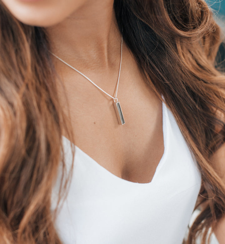 A model wearing the sterling silver small bar memorial necklace by close by me jewelry from an angle