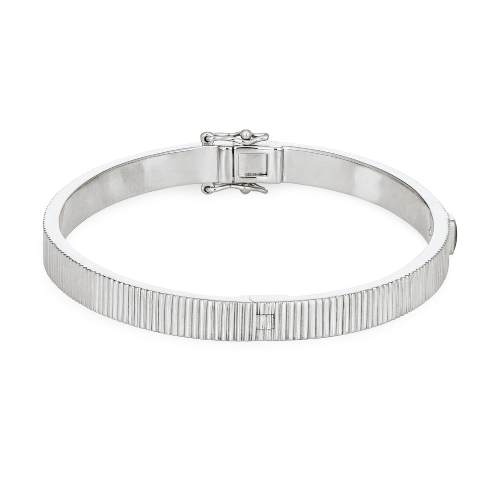 Close By Me's Tessa Bangle Cremation Bracelet in Rhodium Plated Sterling Silver lays flat and turned to the right in a closed position against a solid white backdrop.