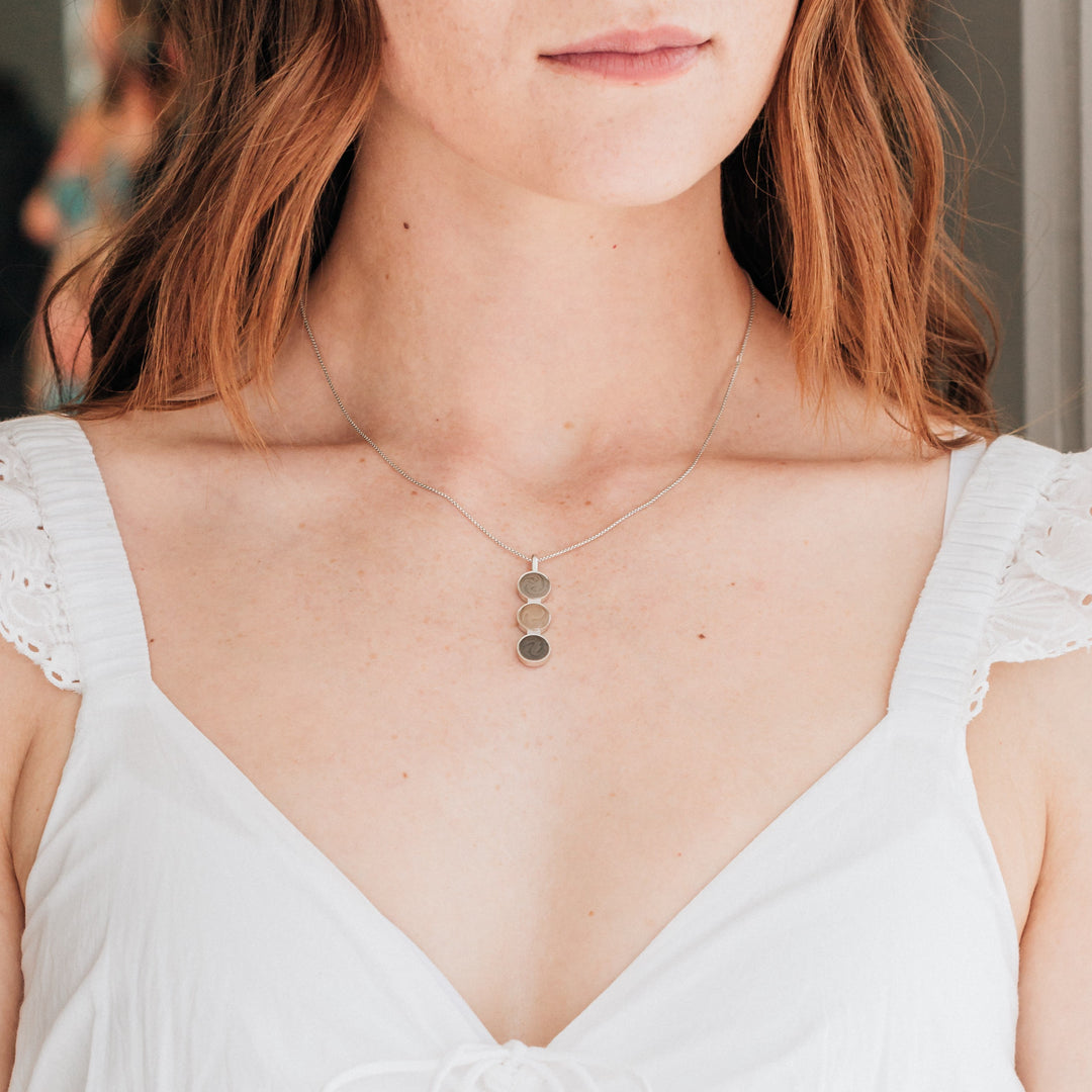 A model in a white dress with red hair wearing close by me jewelry's Triple Setting Circle Cremation Necklace in Sterling Silver