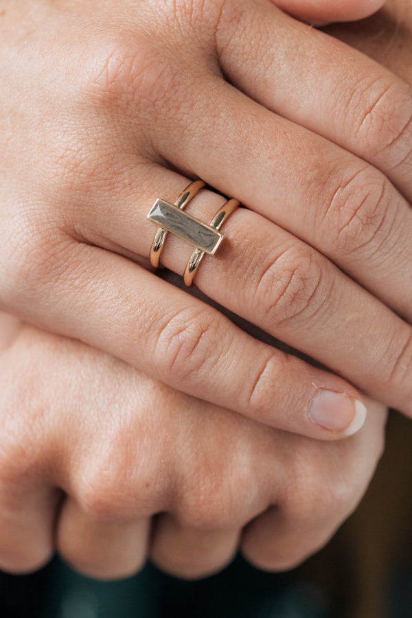 This close up photo shows a model wearing close by me jewelry's 14K Yellow Gold Bar Ashes Ring design on her ring finger