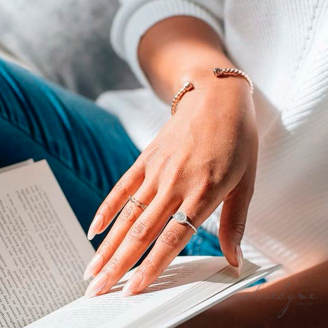This photo shows a model wearing close by me jewelry's 14K Rose Gold Four Setting Ring and Cable Cuff Bracelet and Sterling Silver Cable Band Ring
