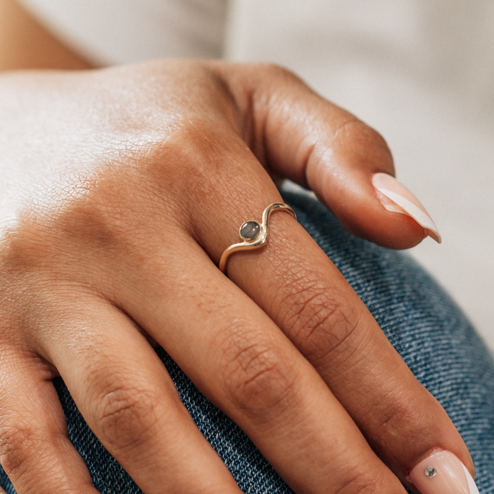 This is a close up photo that shows the 14K Yellow Gold Chevron Circle Cremation Ring design in 14K Yellow Gold on a model's index finger
