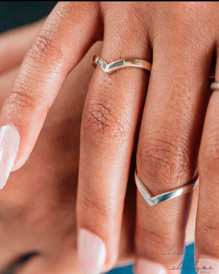 This photo is a close up of the 14K Yellow Gold Chevron Ring set with cremains and the Sterling Silver Chevron Companion Ring by close by me jewelry on a models hand