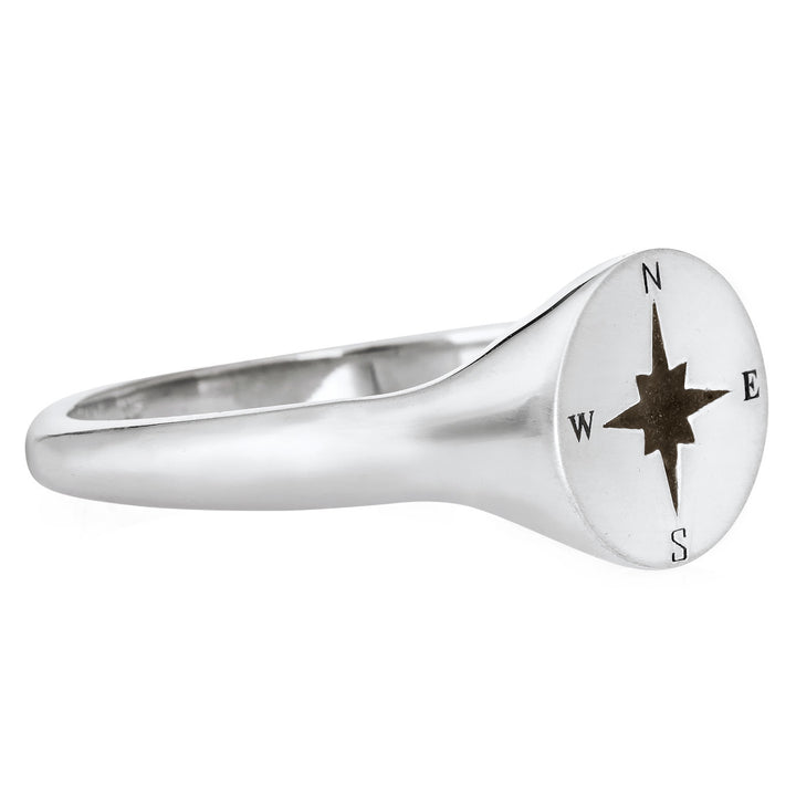 Pictured here is the Men's Compass Signet Cremation Ring design by close by me jewelry in 14K White Gold from the side. The face of this ring is round with a Compass-Rose Motif and a dark ashes setting.