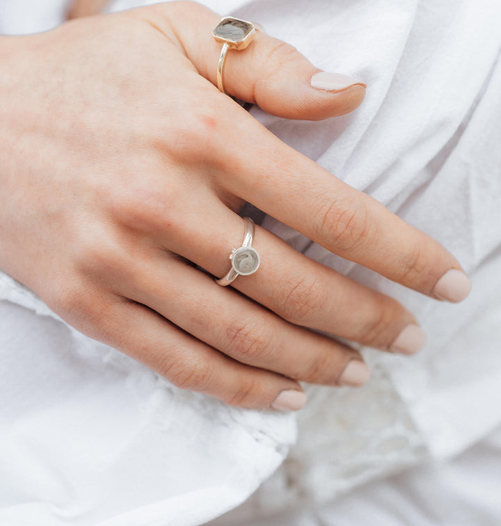 Pictured here is a model wearing the Sterling Silver Fleur de Lis Ring for ashes by close by me jewelry on her middle finger