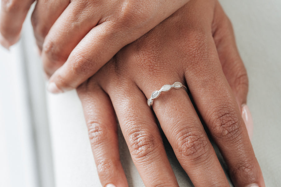 This photo shows the Sterling Silver Four Setting Cremation Ring on a model's middle finger