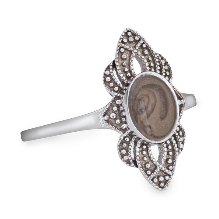 Pictured here is a close-up side view of Close By Me Jewelry's vintage-style World War II Cremation Ring in 14K White Gold set against a solid white background. This version of the ring has a larger oval bezel containing solidified cremated remains. The ashes setting in this photo is medium gray in color and features a distinct swirl pattern.