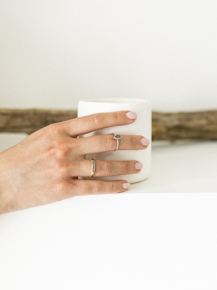 Pictured here is a model wearing close by me jewelry's Marquee Stacking Ring in Sterling Silver being worn as a midi ring with the 14K Yellow Gold Smooth Band Ring on a different finger