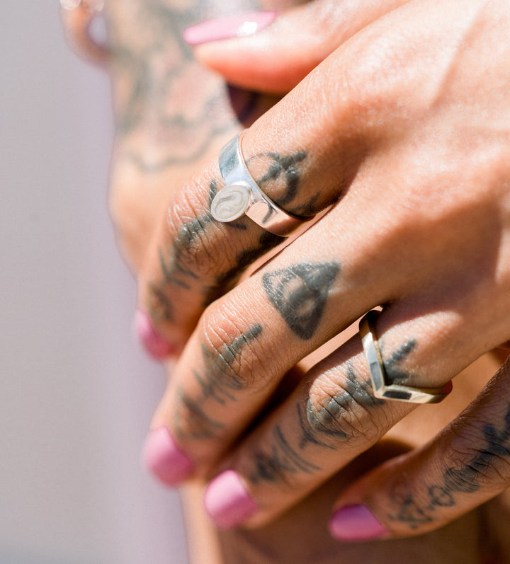 Pictured here is a close up of the Oval Crown Cremains Ring designed by close by me jewelry in Sterling Silver on a models' index finger