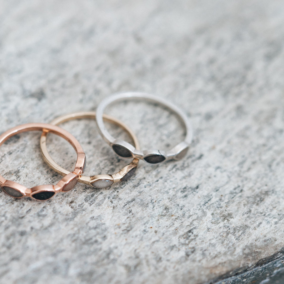 This photo shows a different angle of several mixed metal cremation rings by close by me jewelry lying flat on a stone