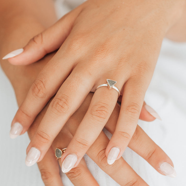 This photo shows a model with close by me jewelry's Sterling Silver Triangle Ashes Stacking Ring on her ring sizer