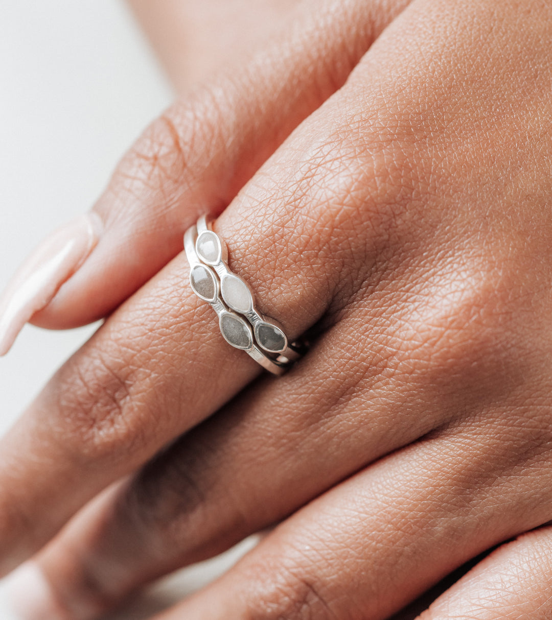Pictured here are close by me jewelry's Sterling Silver Two Setting and Three Setting Cremation Rings stacked on a model's index finger