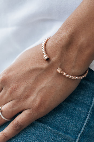 Rose gold cable cuff ashes bracelet on the arm of a model wearing a white t-shirt and blue jeans