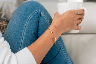 14k rose gold cable cuff solidified ashes bracelet on a woman holding a mug of a warm drink