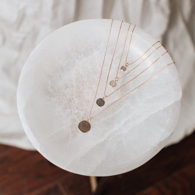 close by me jewelry's dome pendant series in multiple metals lying flat on a white marble table in a chevron formation