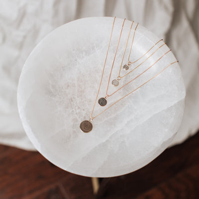 All sizes of the dome pendant series with ashes designed by close by me in various metals lying flat on a white marble table