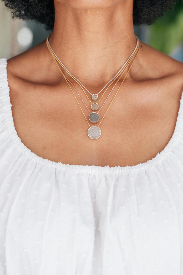 This photo shows all of the sizes of Sliding Solitaire Cremains Necklace in different metal types designed by close by me jewelry around a model's neck