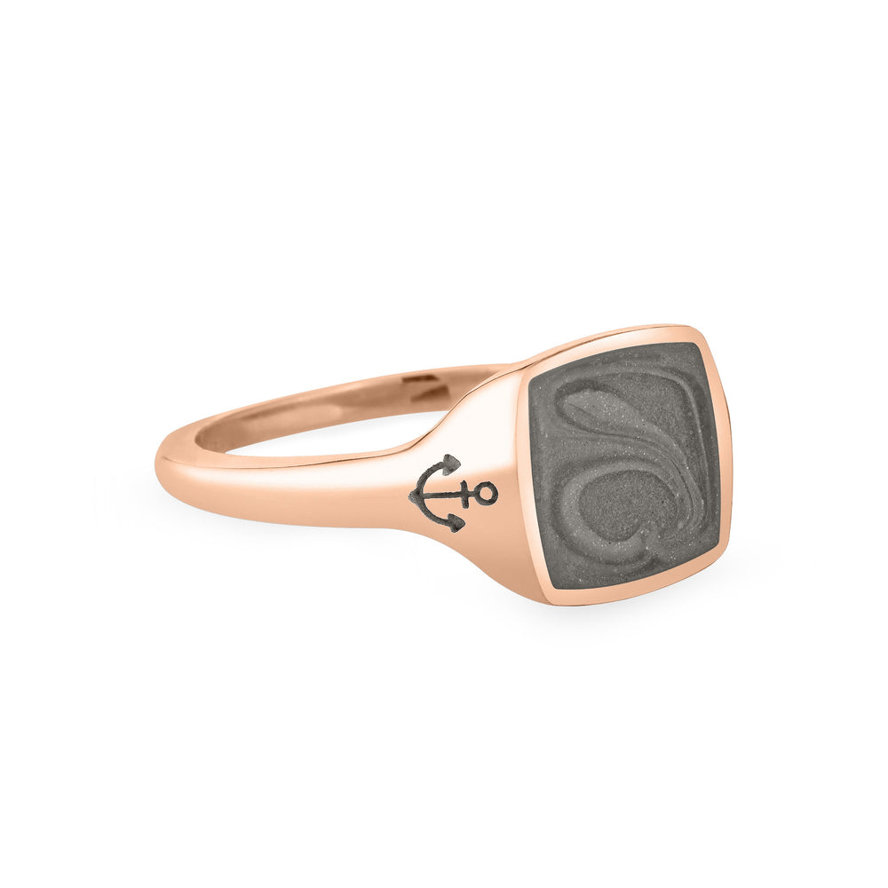 Close By Me's Anchor Signet Cremation Ring in 14K Rose Gold floats in the center of a solid white background, facing right. The square-shaped cremation setting is dark grey in color and has a bold, visible swirl. The anchor imprint in the band, on the left side of the setting, is clearly visible.