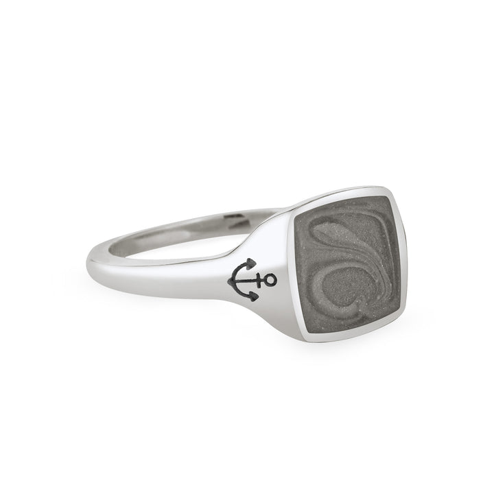 Close By Me's Anchor Signet Cremation Ring in Sterling Silver floats in the center of a solid white background, facing right. The square-shaped cremation setting is dark grey in color and has a bold, visible swirl. The anchor imprint in the band, on the left side of the setting, is clearly visible.