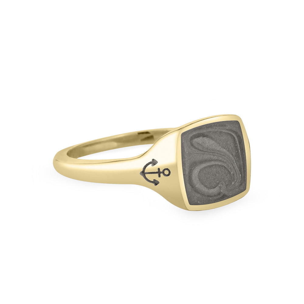 Close By Me's Anchor Signet Cremation Ring in 14K Yellow Gold floats in the center of a solid white background, facing right. The square-shaped cremation setting is dark grey in color and has a bold, visible swirl. The anchor imprint in the band, on the left side of the setting, is clearly visible.
