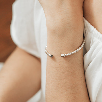 14k White gold cable cuff cremation bracelet with solidified ashes shown on the wrist of a model with a white top