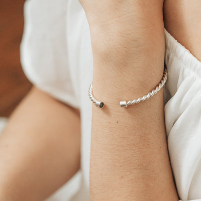 14k Yellow Gold Cable Cuff Cremation Bracelet with ashes pictured on a model wearing white, close up on the wrist