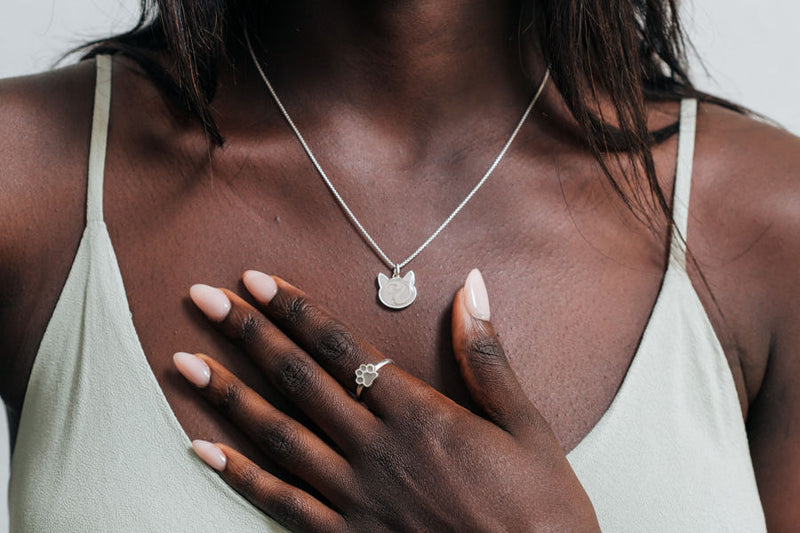 A model with dark skin in a light green dress wearing the Cat Necklace with ashes by close by me jewelry in sterling silver