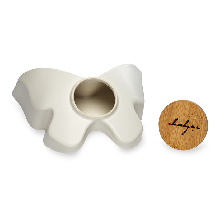 The bottom of Close By Me's Ceramic Butterfly Urn next to the branded bamboo lid.