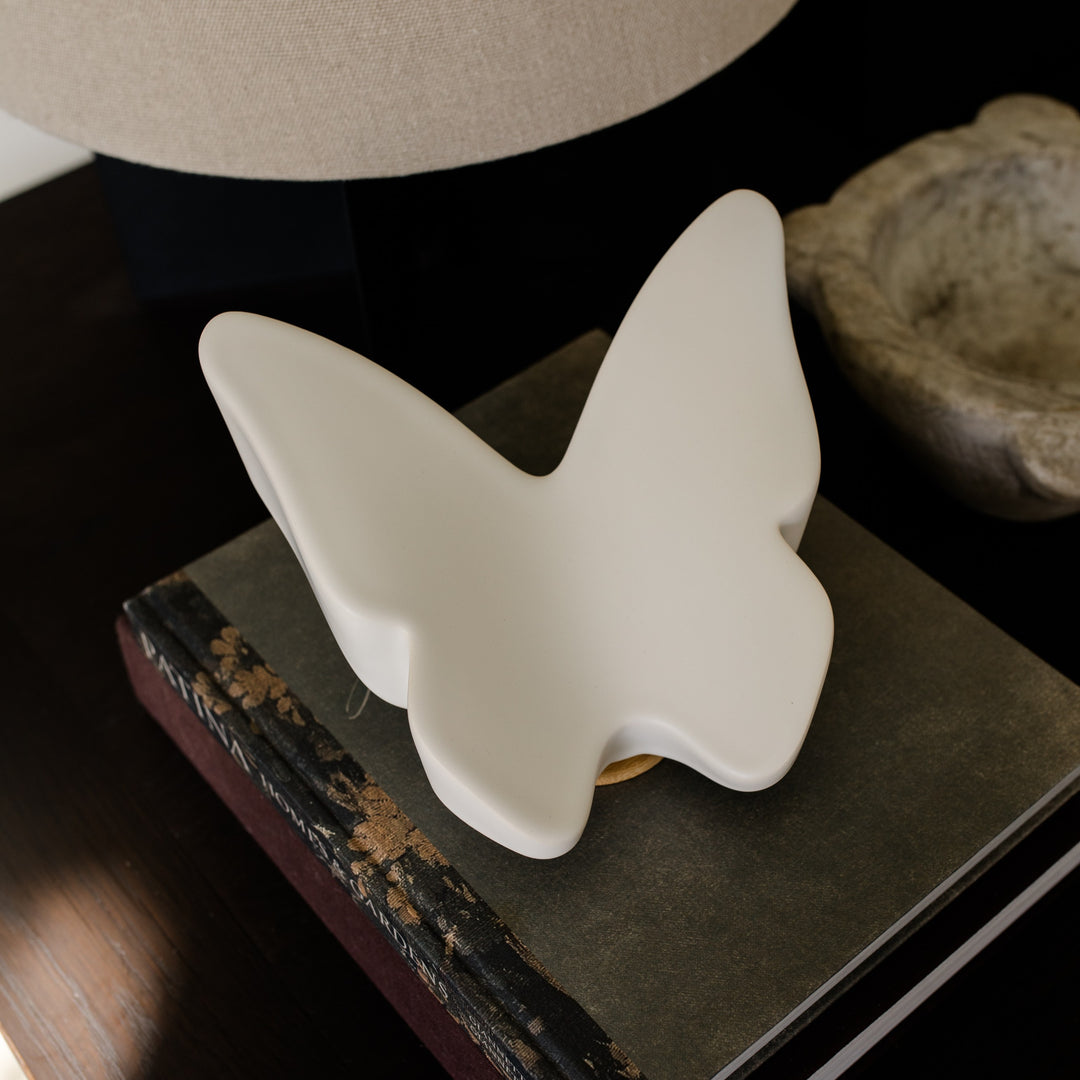 White ceramic butterfly cremation urn on a stack of books