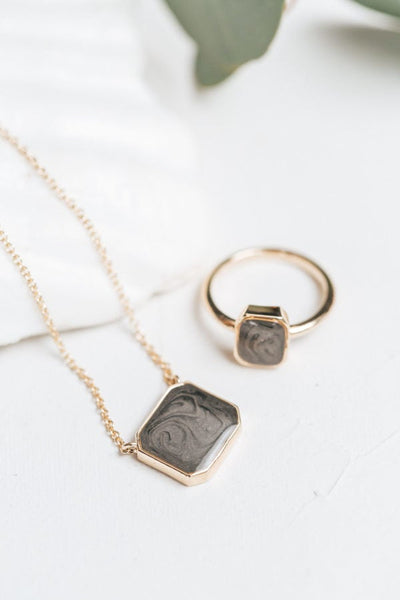 The cushion art deco ashes collection by close by me jewelry in 14k yellow gold lying flat against a white background