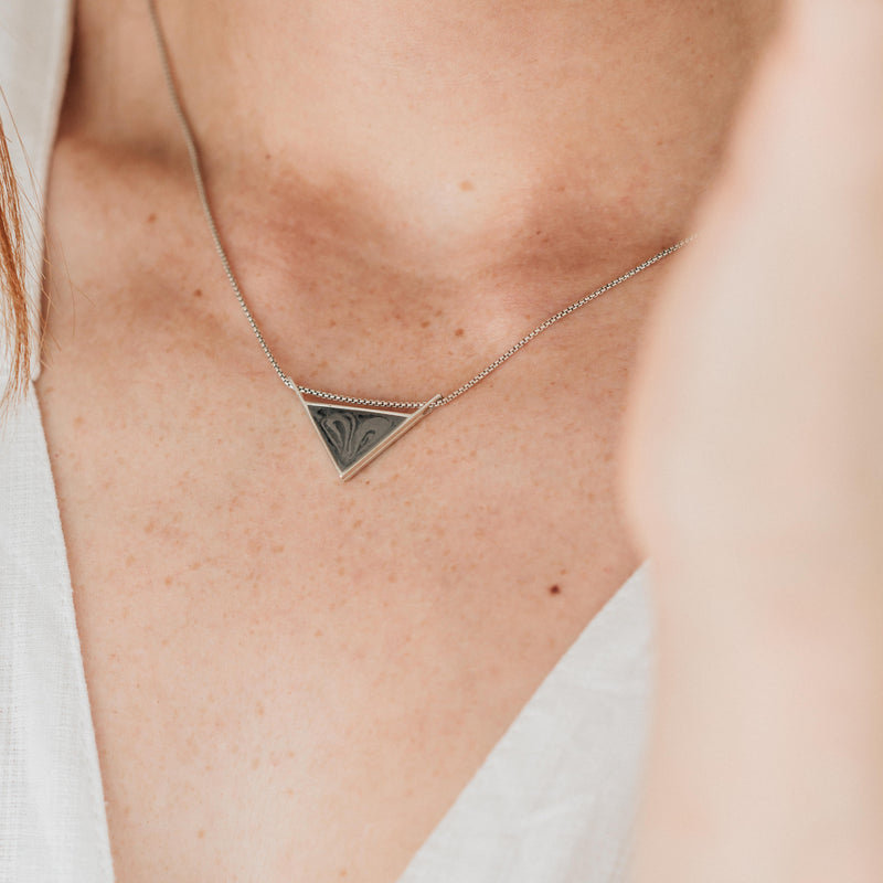 A close up of a light skinned model in a white top wearing the detailed triangle sliding necklace in sterling silver by close by me jewelry