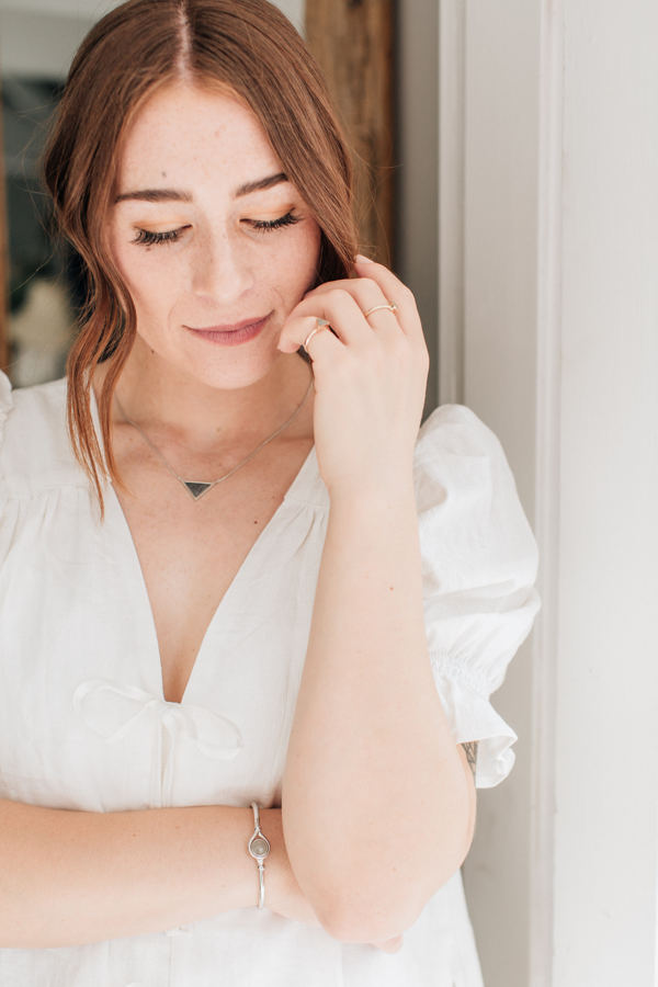 The sterling silver detailed sliding ashes triangle cremation necklace being worn by a model in a white dress