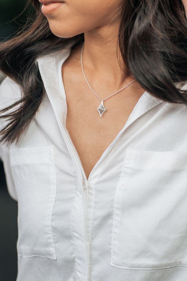 Pictured here is a tan model with dark hair wearing a white button-up and close by me jewelry's Sterling Silver Diamond Necklace with cremains
