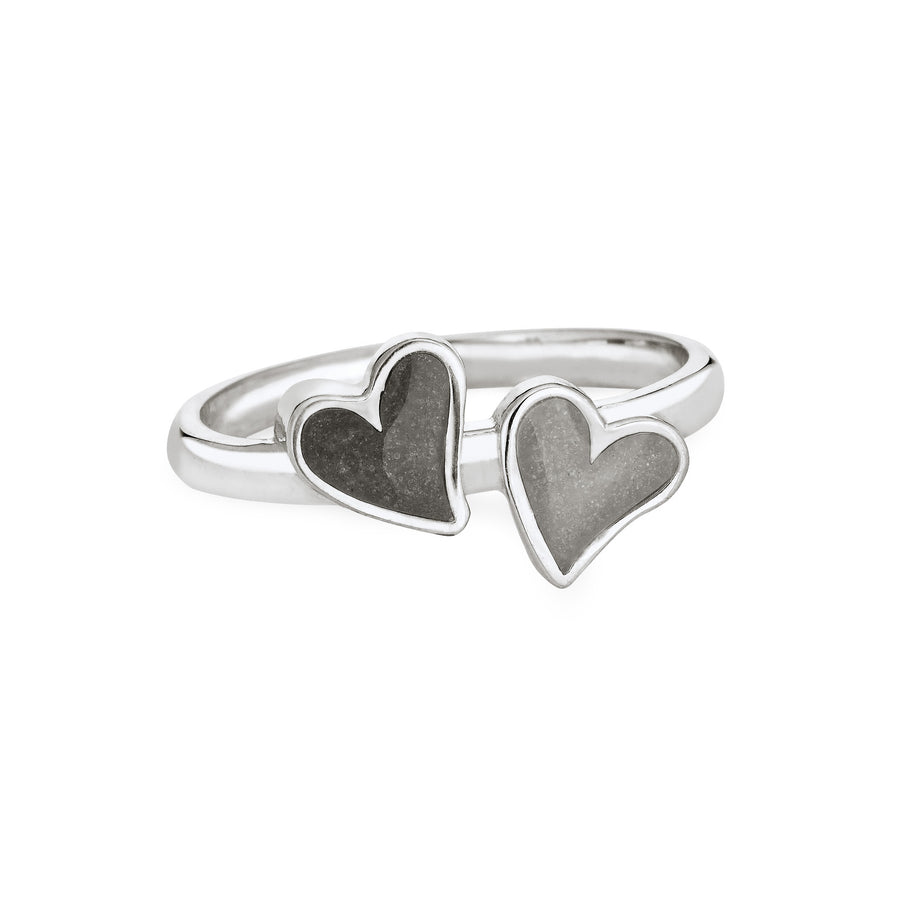 Front view of Close By Me's Sterling Silver Double Heart Cremation Ring, floating against a white backdrop. The left heart has a darker ashes setting, and the right heart has a light grey ashes setting.