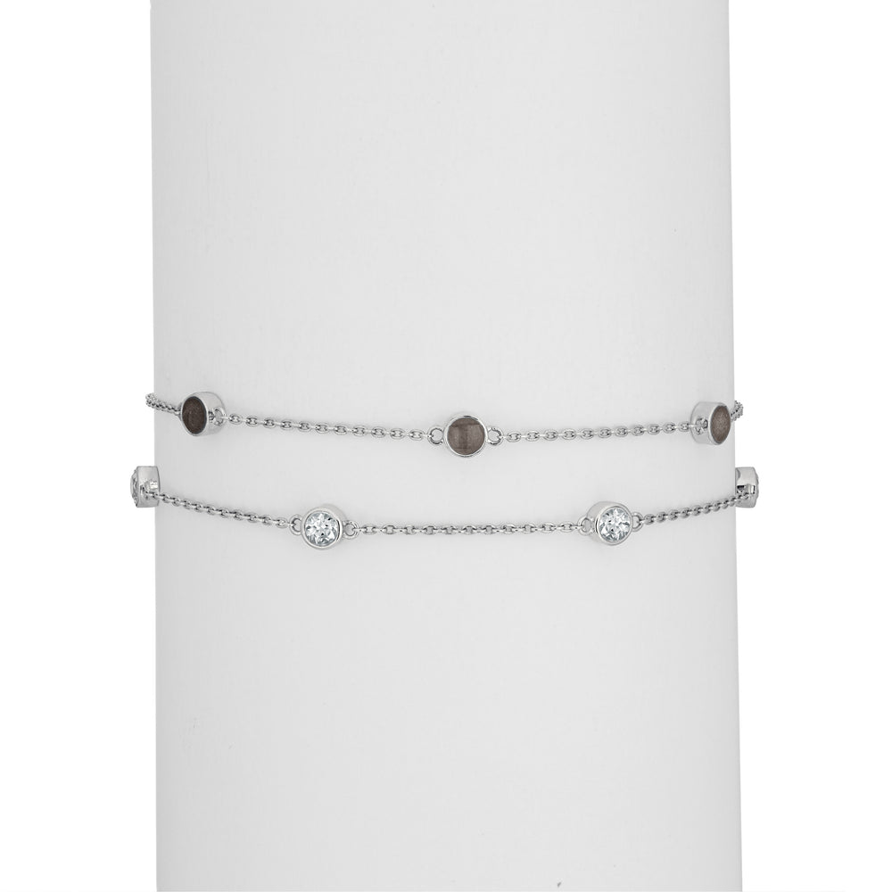 Close By Me's Double Strand Cremation Bracelet in 14K White Gold on a cylindrical white holder with the strand of three ash-filled charms parallel atop the strand of four white topazes.