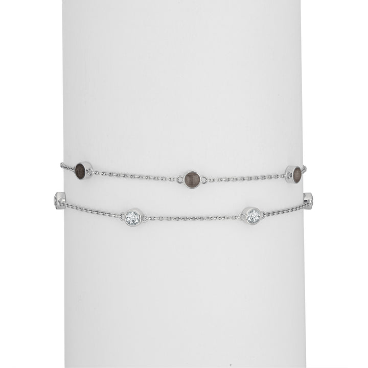 Close By Me's Double Strand Cremation Bracelet in 14K White Gold on a cylindrical white holder with the strand of three ash-filled charms parallel atop the strand of four white topazes.