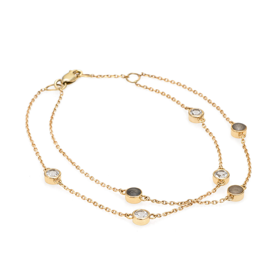Close By Me's Double Strand Cremation Bracelet in 14K Yellow Gold laid flat in a circular, closed position with the strand of four white topazes crossing the strand of three ash-filled charms.