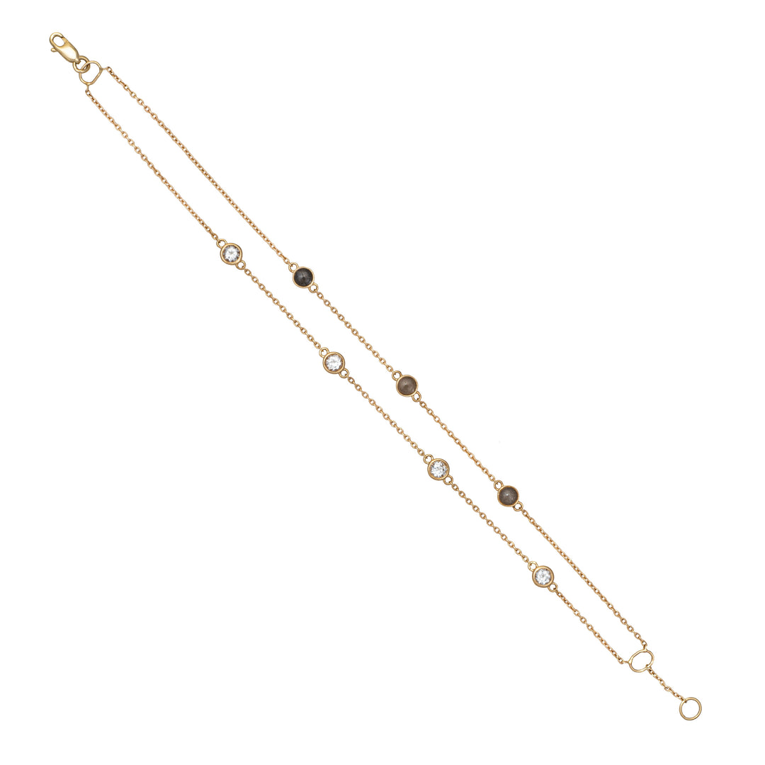 Close By Me's Double Strand Cremation Bracelet in 14K Yellow Gold laid flat in a vertical, opened position stretching diagonally across a solid white background with the strand of four white topazes parallel to the strand of three ash-filled charms.