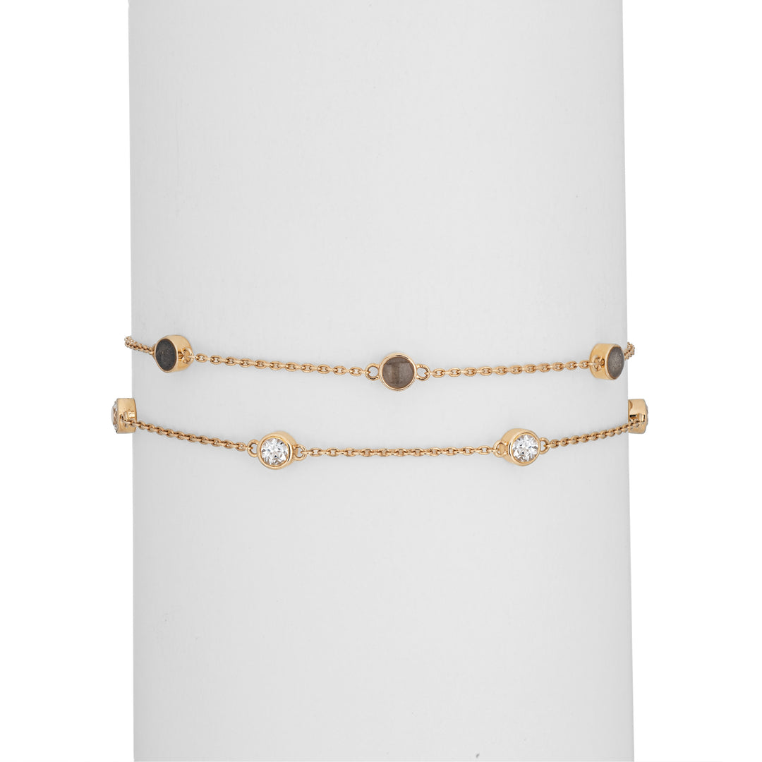 Close By Me's Double Strand Cremation Bracelet in 14K Yellow Gold on a cylindrical white holder with the strand of three ash-filled charms parallel atop the strand of four white topazes.