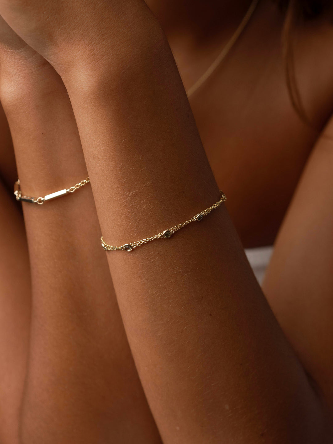 Close-up of Close By Me's Double Strand Birthstone Bracelet in 14k yellow gold on a model's wrist.